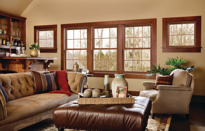 A living room with combined window material types &mdash; vinyl window frames with wooden molding to match the room.