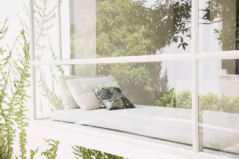 A box bay window with a cushion and pillows for additional seating.