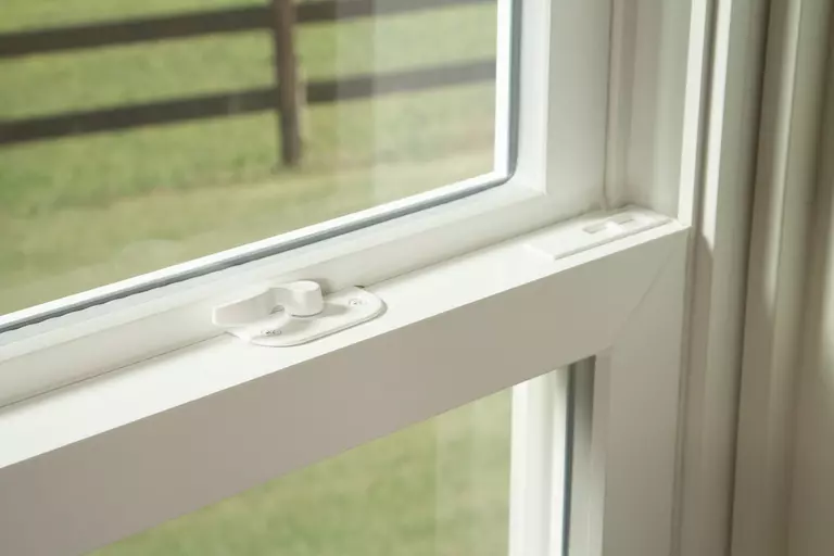 A closeup of a lock on a white window frame.