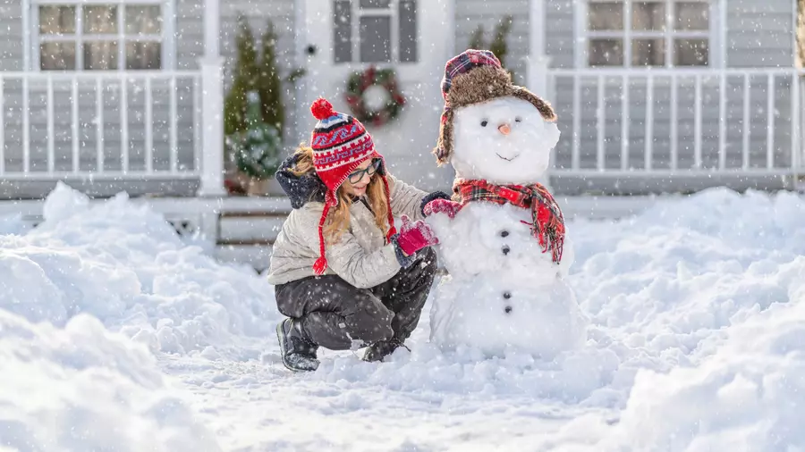 A girl doing her favorite fun winter activity of building a snowman