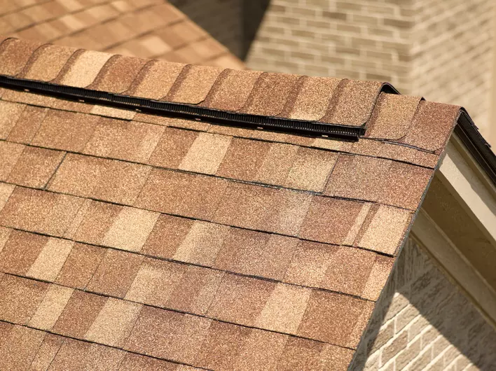 Up close view of the detailed material of slate and asphalt shingles on the roof of a brick home