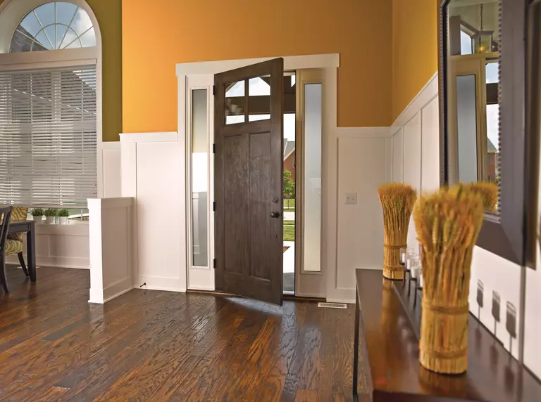 A dark brown front door with a woodgrain texture that’s partially opened.