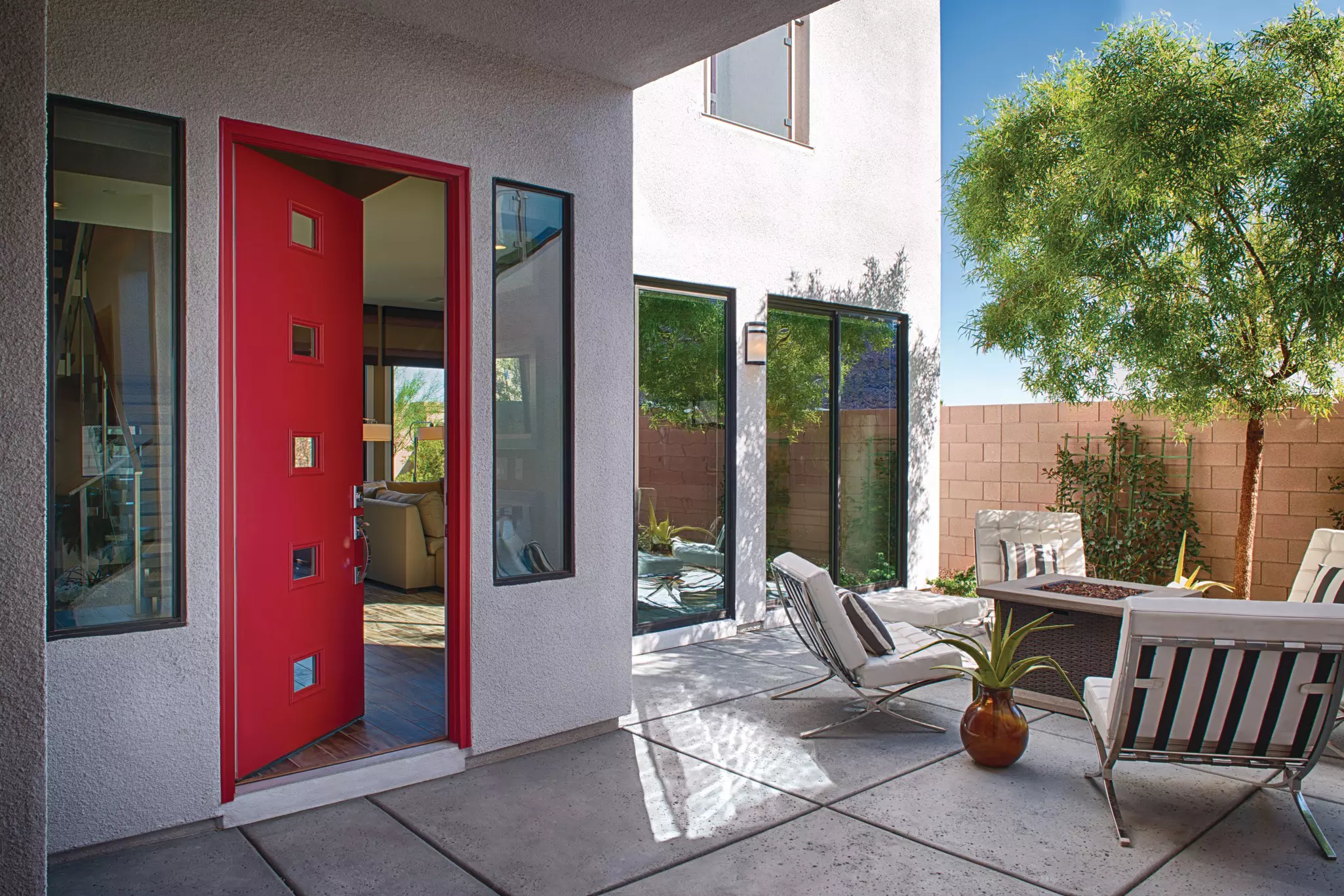 Patio of a contemporary home with a partially open red entry door.