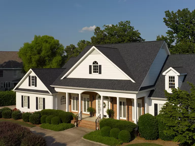 Two-story home with a white and brick exterior and multiple roof faces.