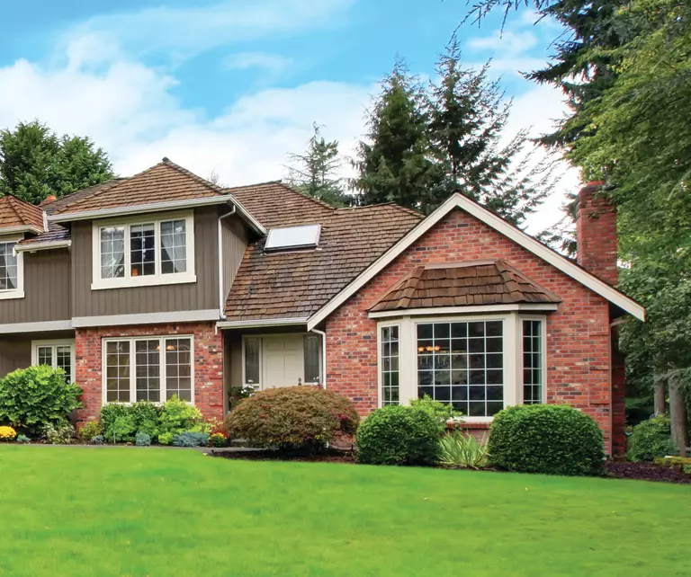 Exterior of a home with several rectangular windows and a bow window with grilles.