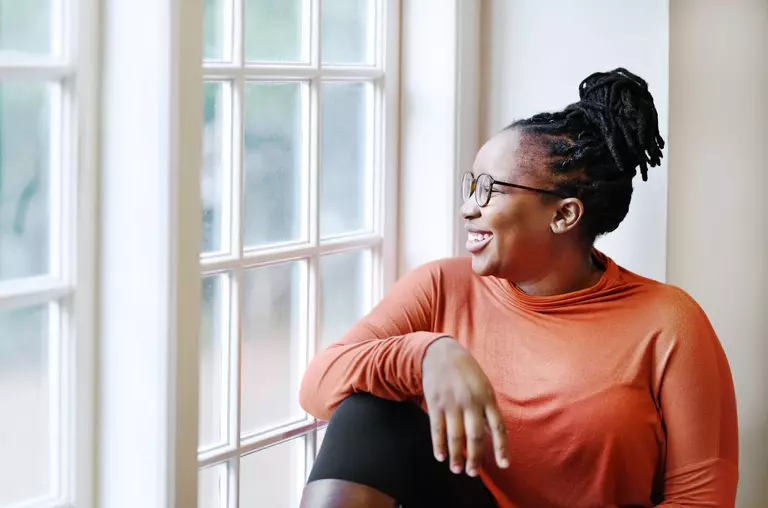 A smiling woman looking outside the low-E glass window of a home.