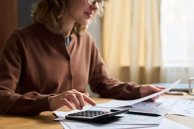 Woman using a calculator and reviewing a document.