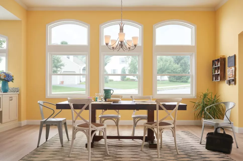 Modern dinning room with double-hung windows that have architectural shapes above as an accent.