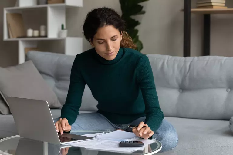 Woman sitting on a couch in her home as she sets a budget to better finance future home improvements.