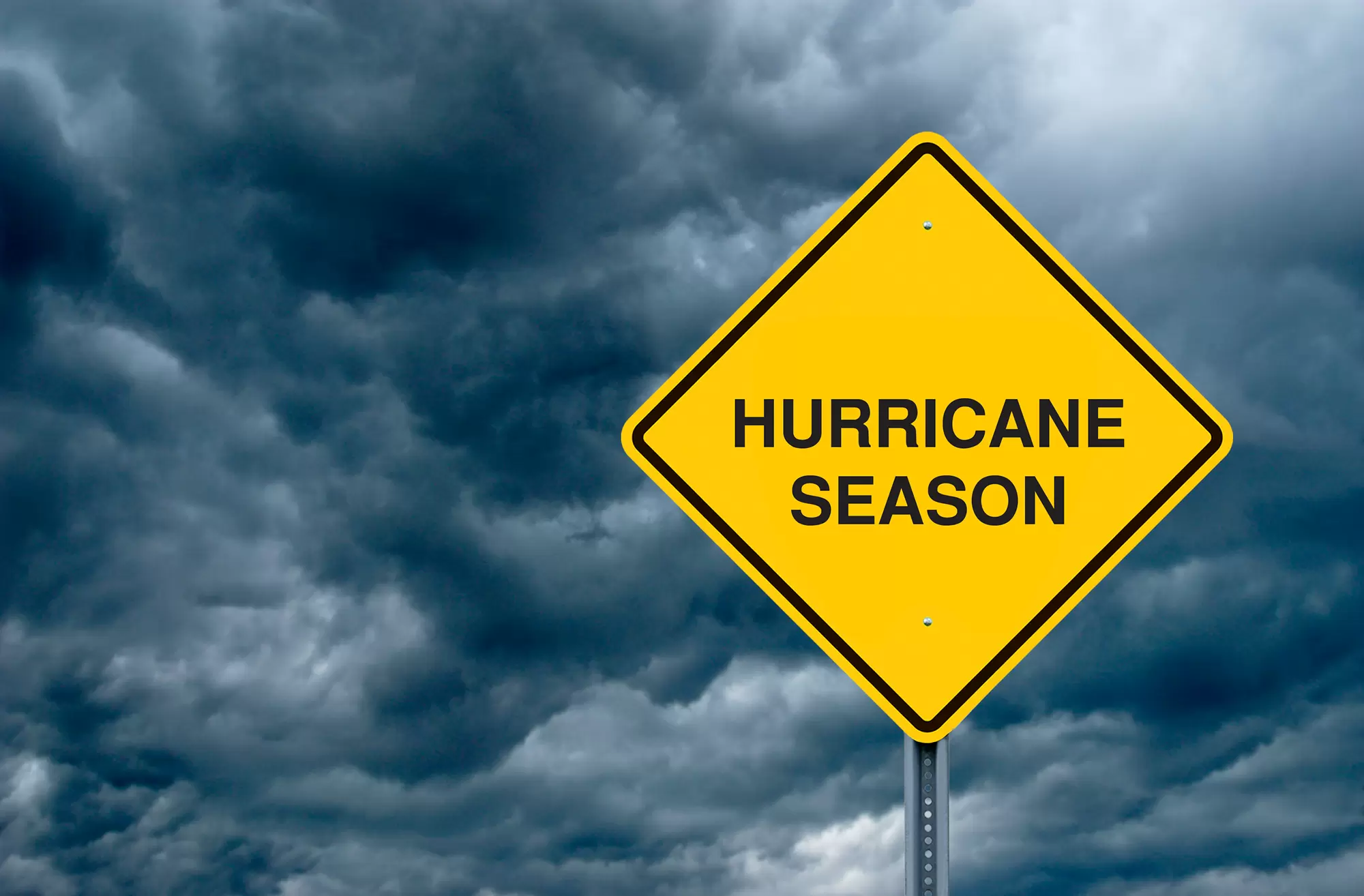 Sign with “hurricane season” in front of a dark and cloudy sky.