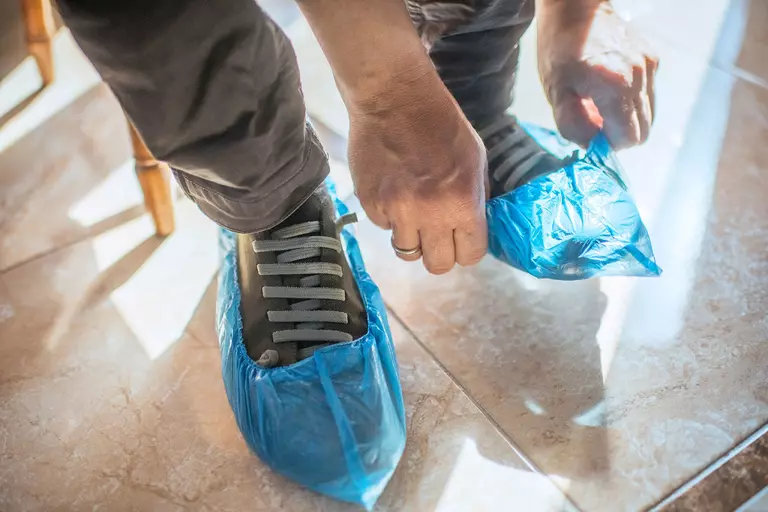 A man putting protective covers over his boots.