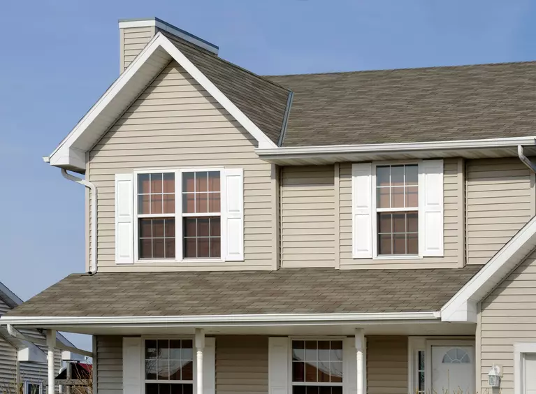 A two-story home with vinyl exterior siding and white raised panel shutters.