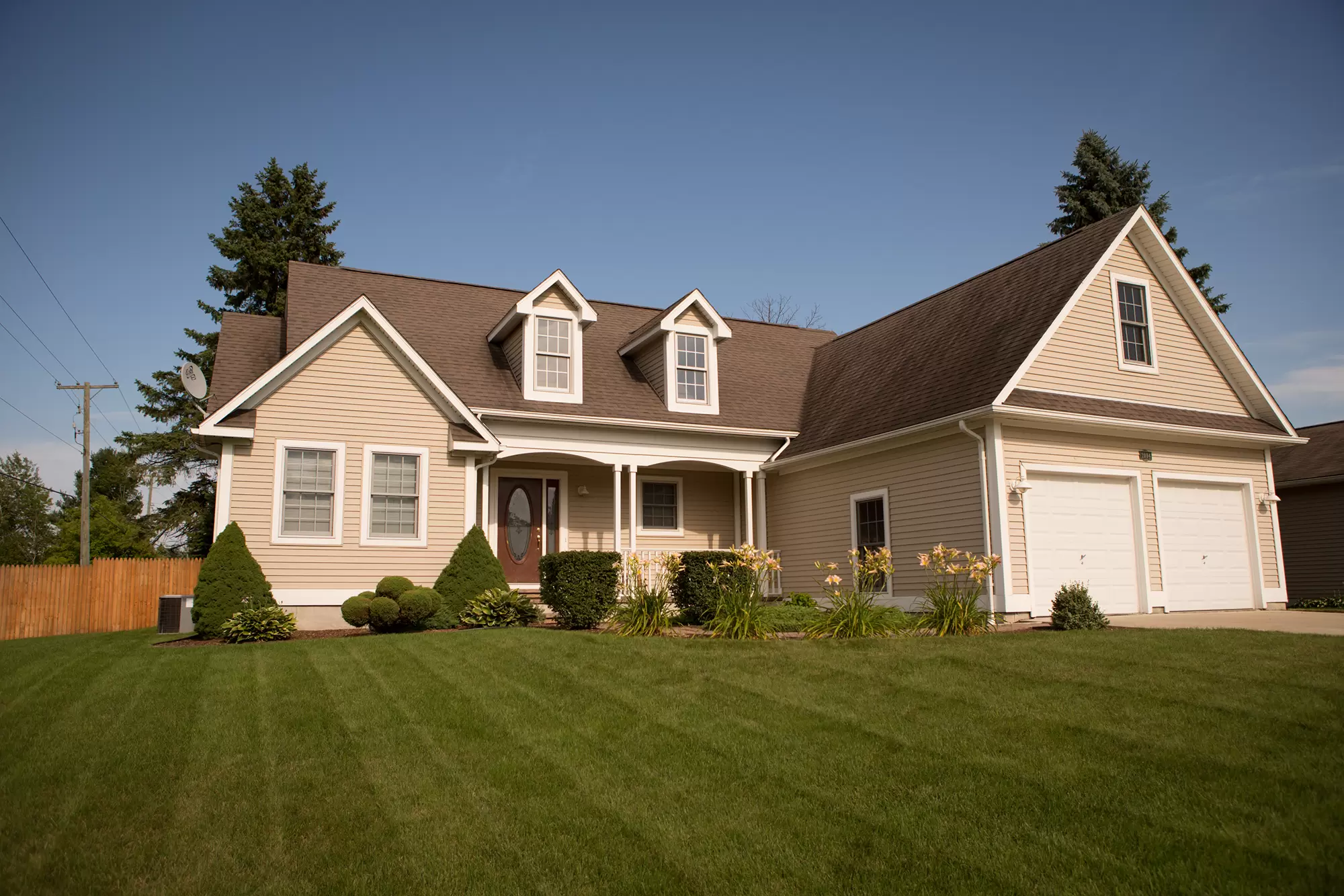 Front yard of a two-story residential home featuring windows with grids.