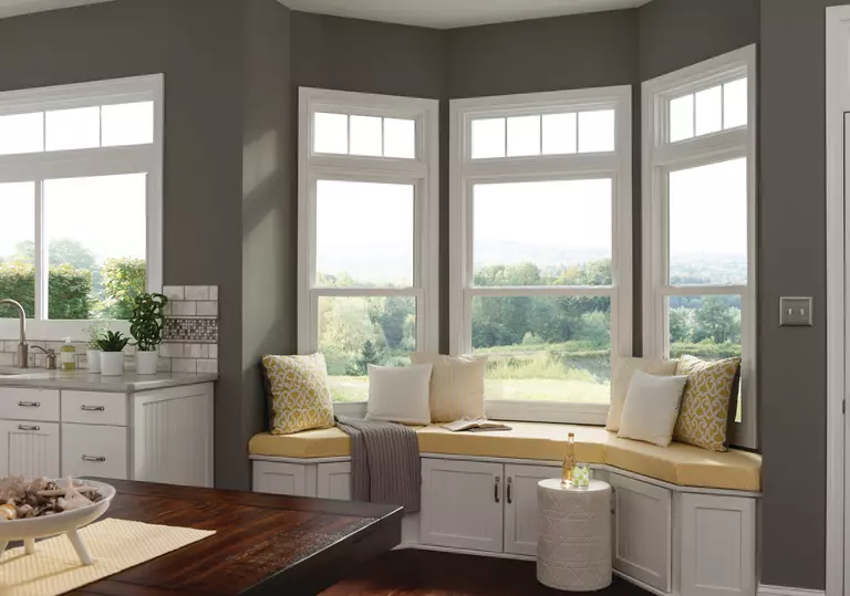 Inside of a home with a bench in front of a bay window.