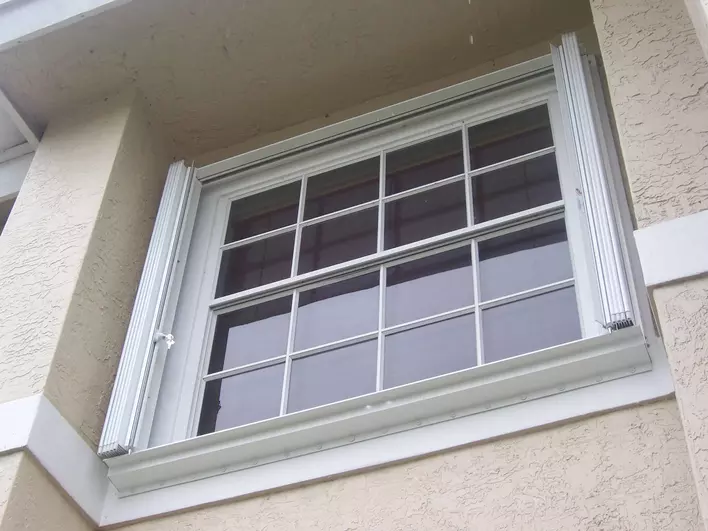 A window equipped with accordion shutters, pictured while pushed back away from the center of the window.