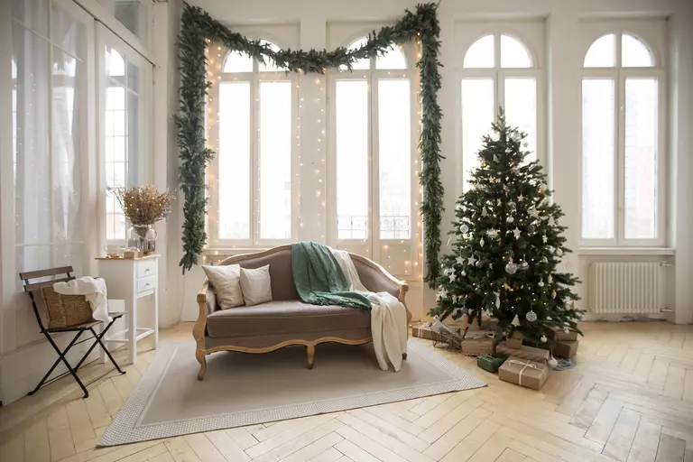 Simple living room furniture with a large garland and traditional holiday tree.