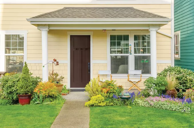 Brown shaker style, smooth entry door on a contemporary home with light yellow siding