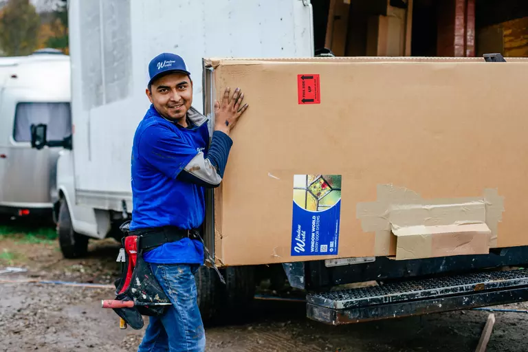 Window World employee carrying a large box of entry door systems during a home renovation.