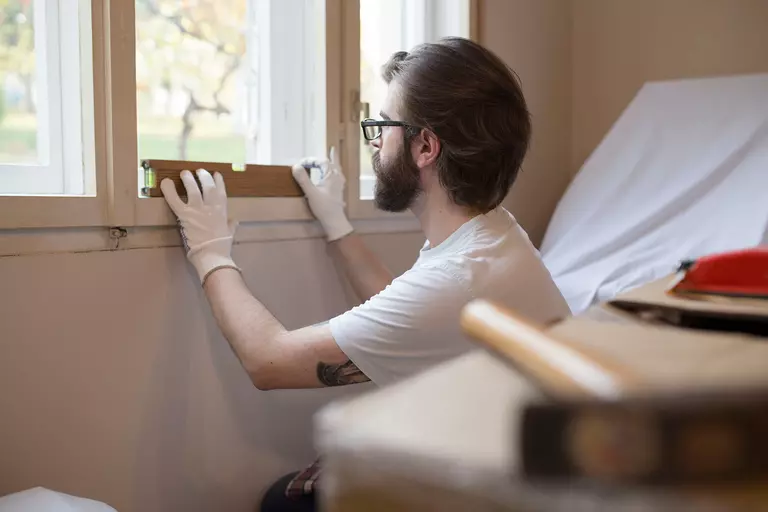 Man using a bubble level to check the straightness of a window frame.