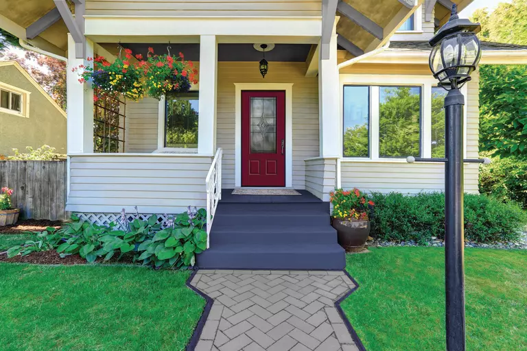 Front view of a home with a red entry door. 