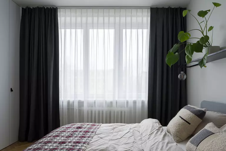 A bedroom with a large window and curtains.