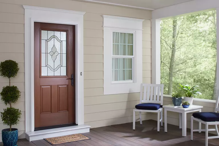 Porch of a home with a wood-look brown entry door.