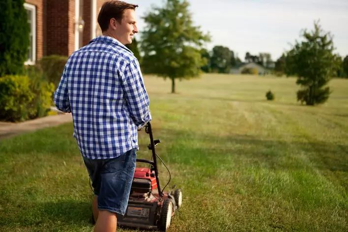 Man mowing the lawn outside of his house