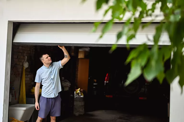 Man inspecting a garage door that is partially opened.