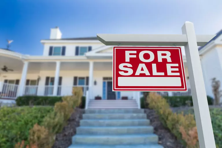 For sale sign in front of a two-story home.