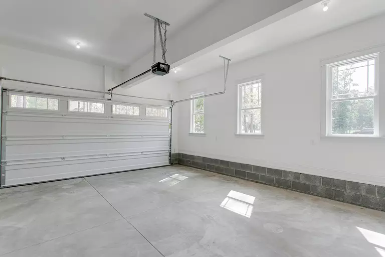 Bright garage space with dual overhead doors and natural light coming through windows.