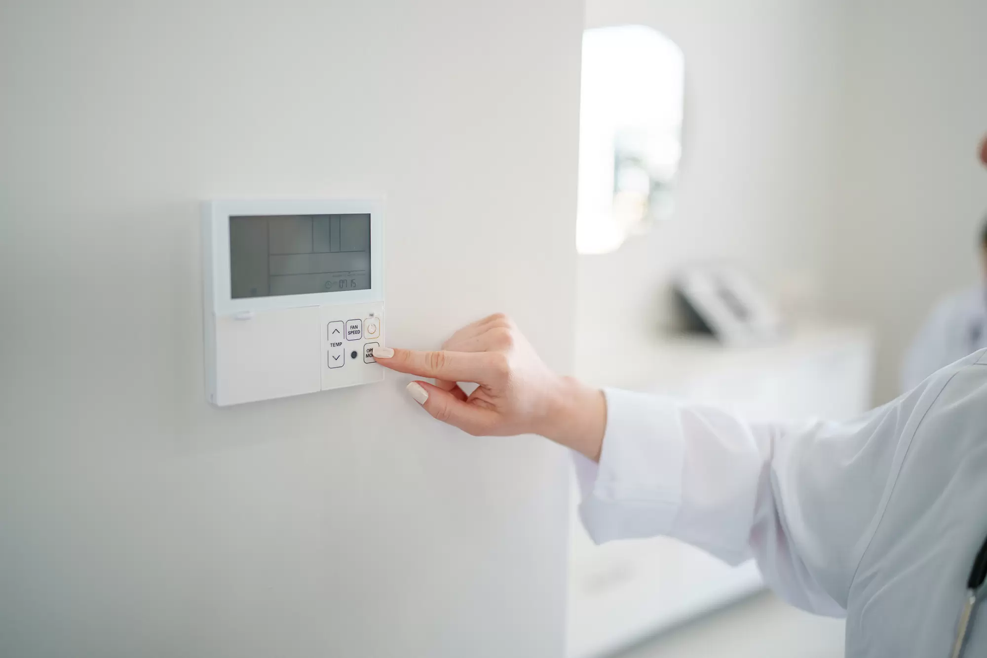 Woman adjusting an indoor thermostat.