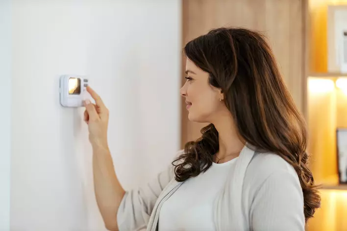 Woman programming the thermostat in her home.