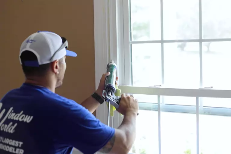 Window World employee caulking a home window.