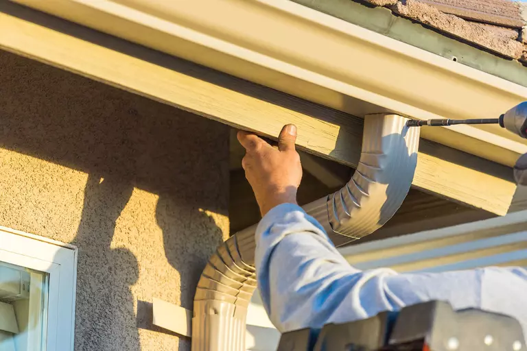 A downspout being installed onto a home.