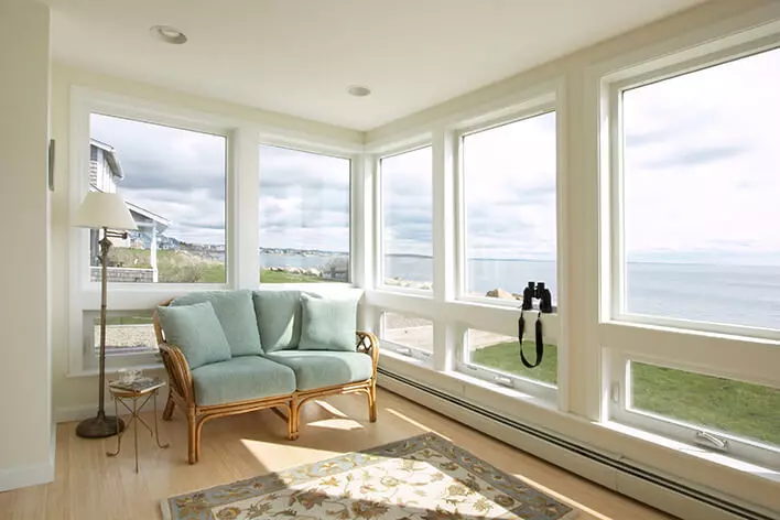 A sunroom with large casement windows providing beach views