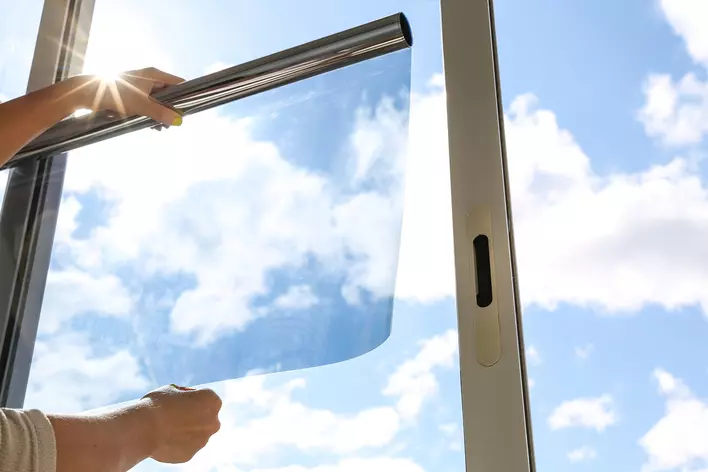 Person placing window film on a large window