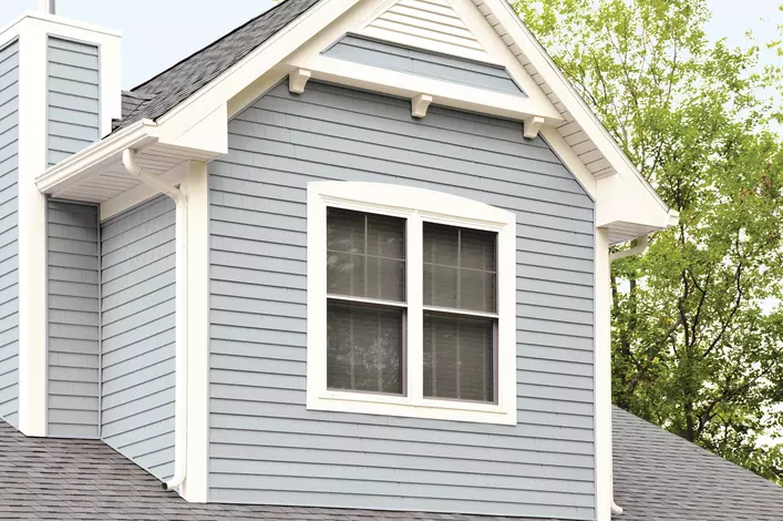 A Low-E window on the second story of a blue home. 