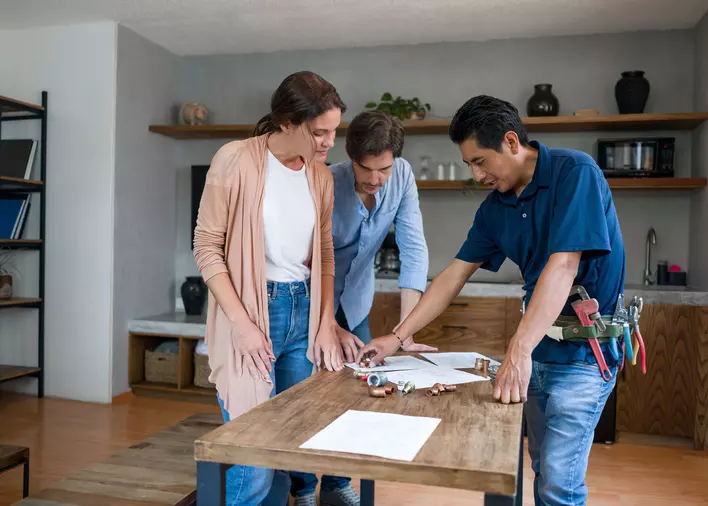 Homeowners and a contractor discussing home renovation ideas over paperwork.