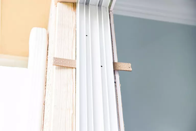 Wooden shims leveling a white door frame