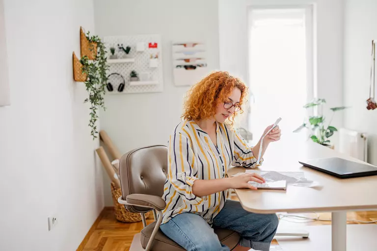 Woman on an office chair reviewing financial documents.