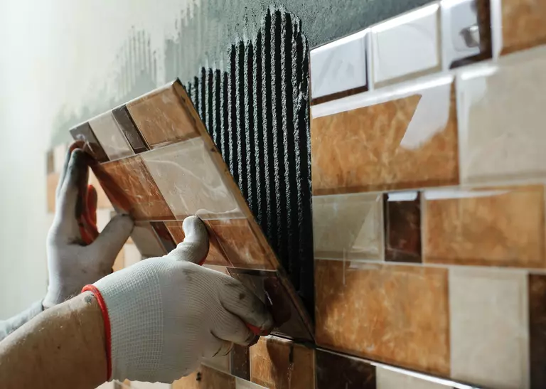 Person replacing the tiles of a bathroom wall.