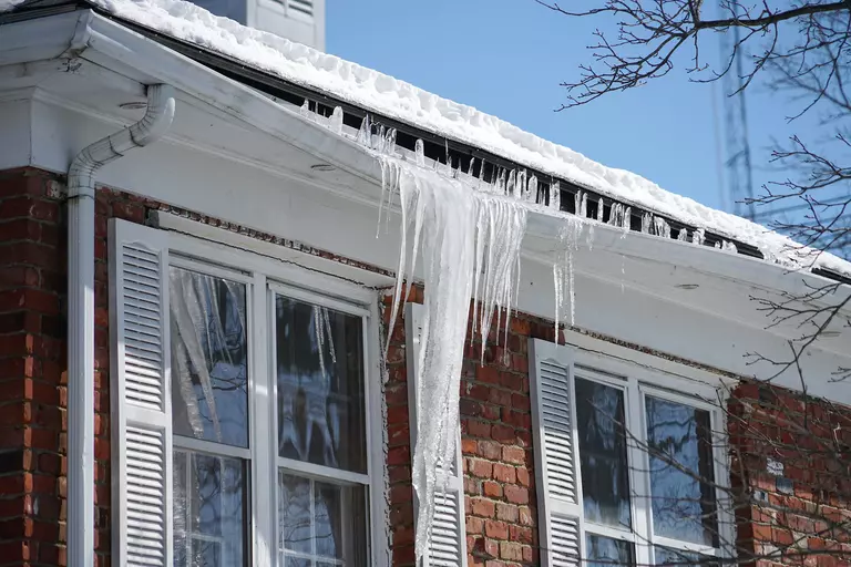 A brick exterior house with an icicle large enough to bend a section of gutters.