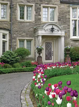 White smooth entry door with full lite wrought iron frame on a home with stone veneer