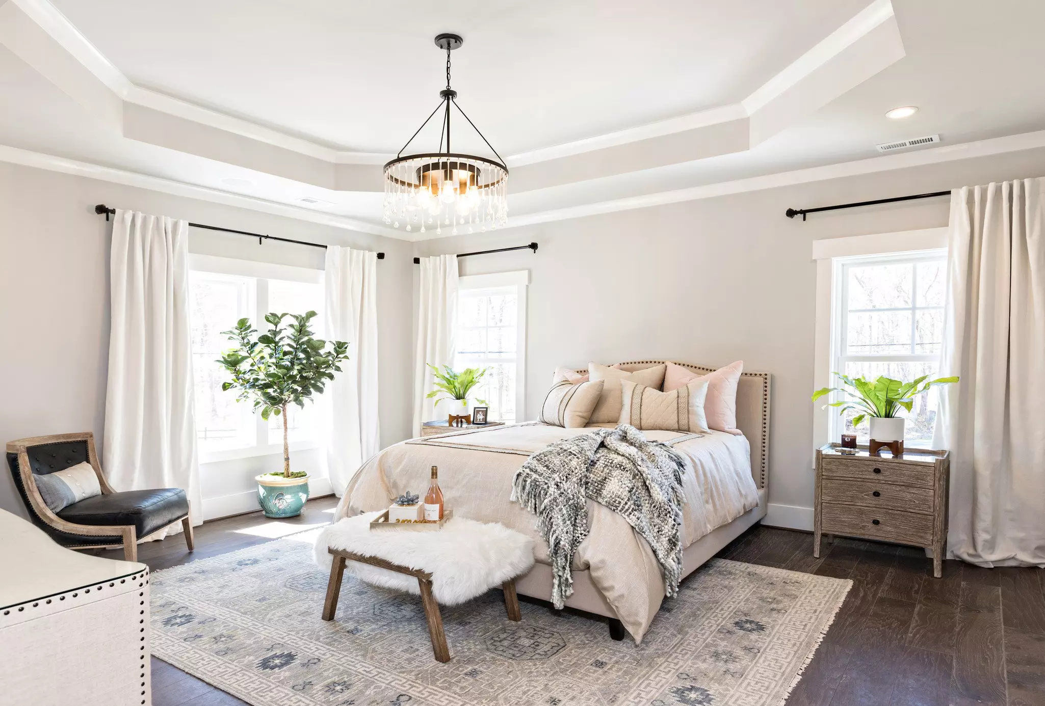 A bedroom with white curtains and windows.