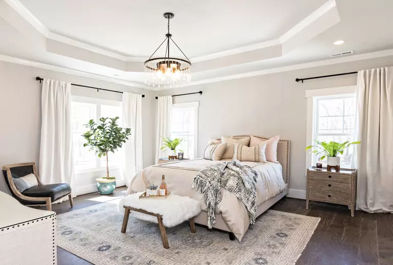 Interior of a bedroom with white windows and furnishings.