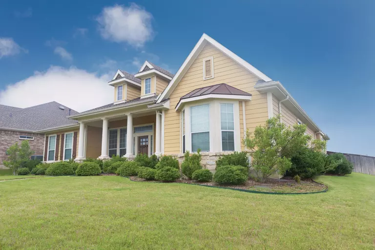 Yellow house with a front bay window and well-tended landscaping.