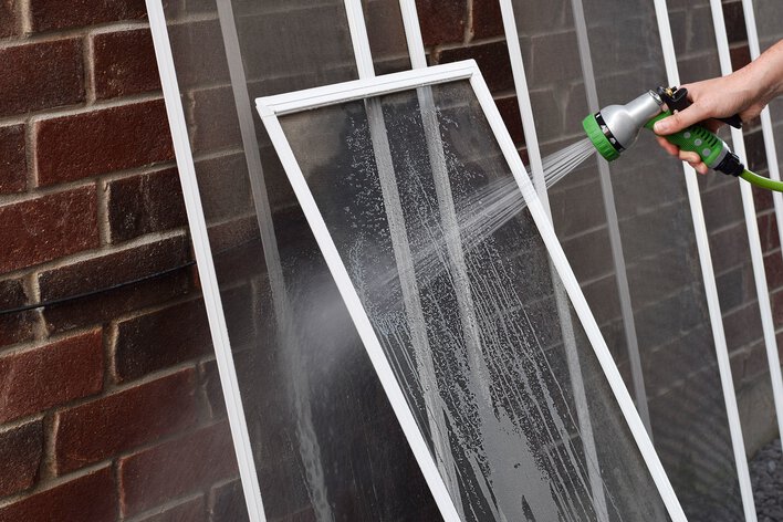 Person rinsing off window screens.