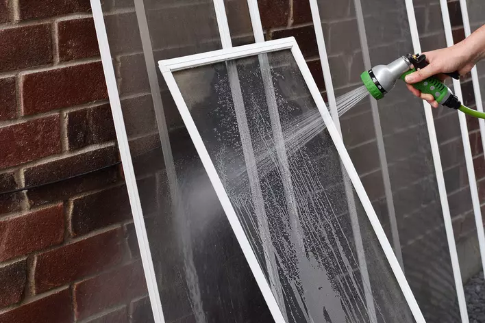 Person rinsing off window screens.
