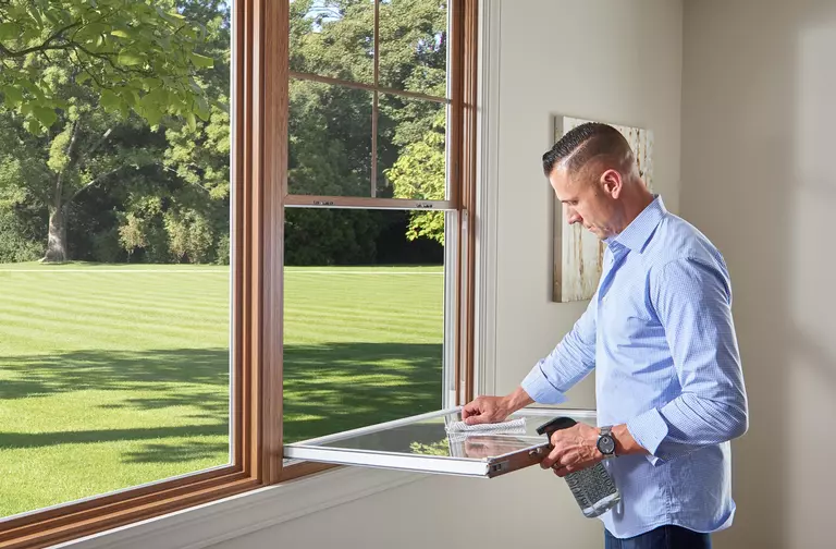 A man cleaning a double-hung window with a tilt-in sash.