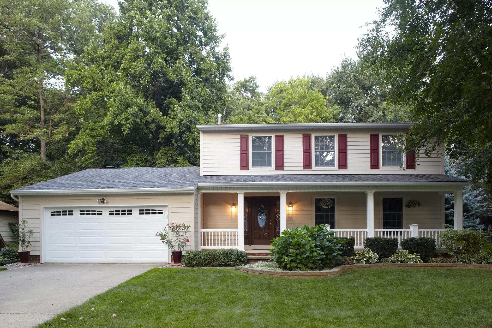Front yard of a two-story home with off-white siding and windows.